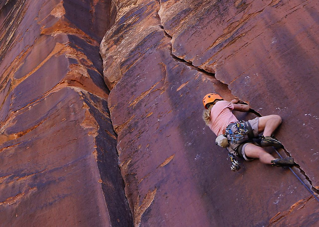 A woman climbs the face of a mountain