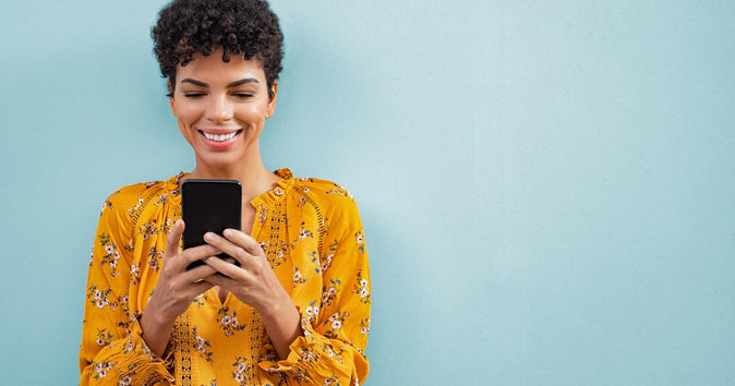 Mulher olhando para o telefone e sorrindo