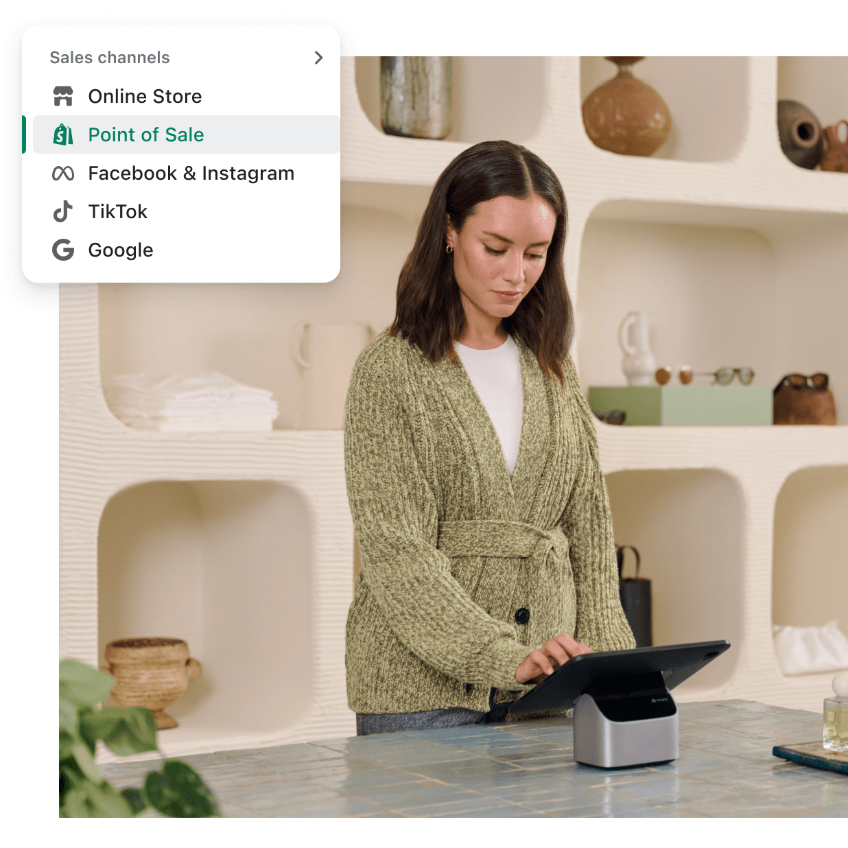 A sales associate stands behind a retail counter using a POS tablet.