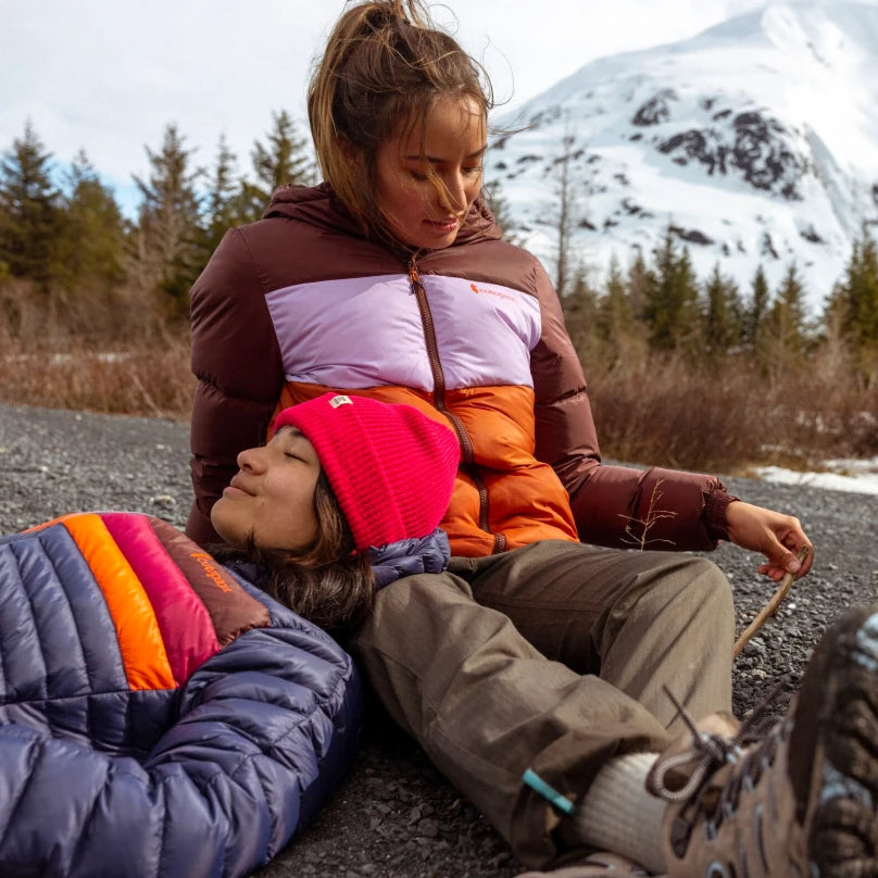 Two female hikers in a mountain scene wearing Cotopaxi jackets