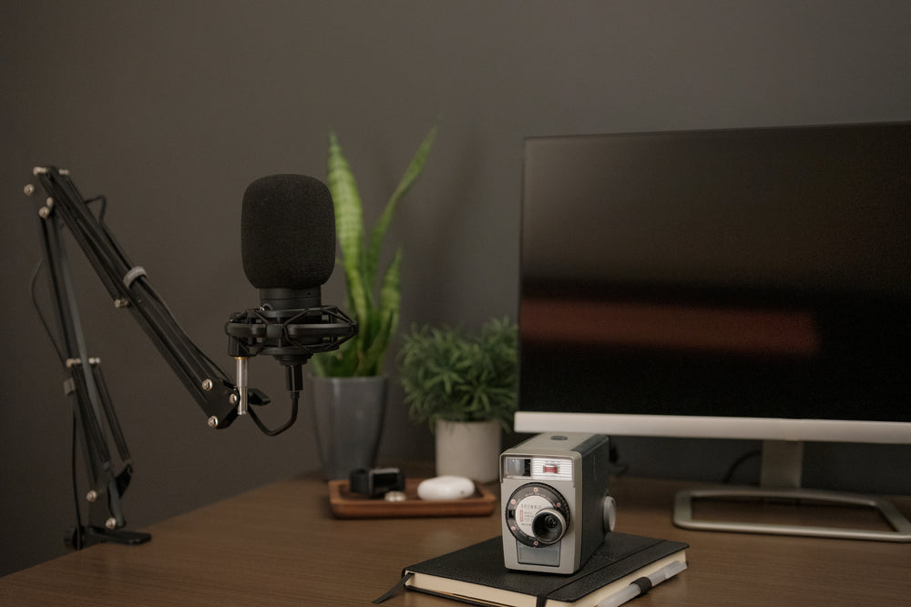 a black microphone accompanied by a notebook and vintage camera