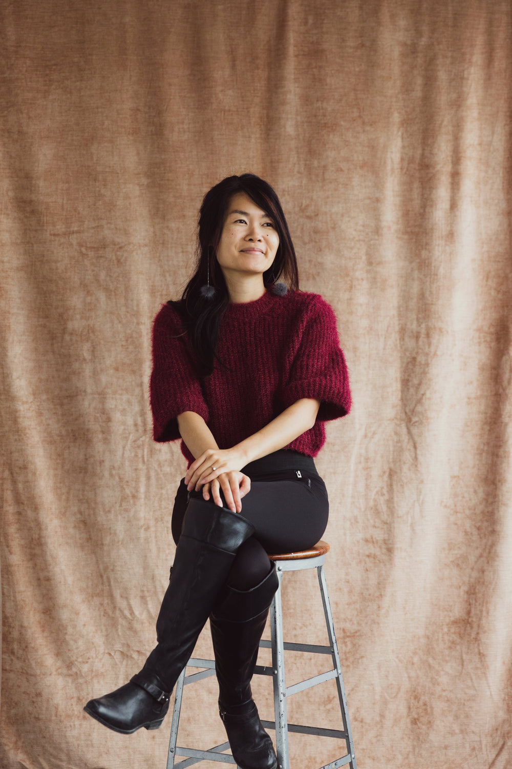 a model perched on a stool smiles