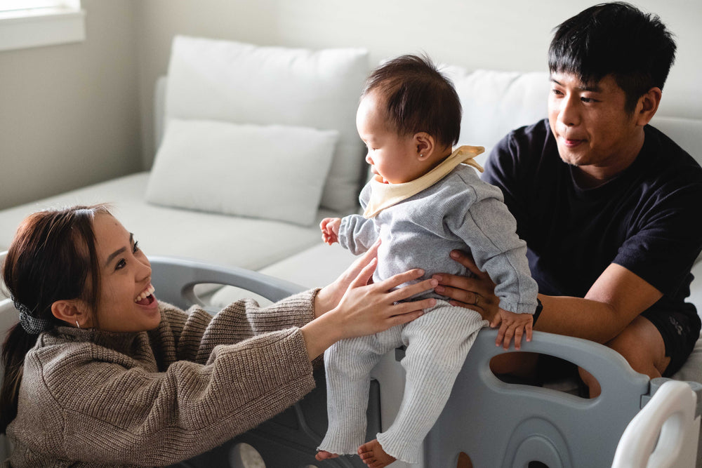 a mother smiles as a father holds their baby