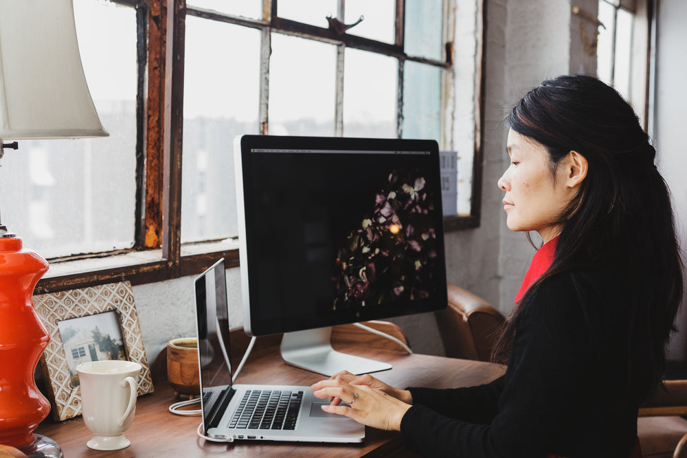 a woman immersed in her laptop and monitor