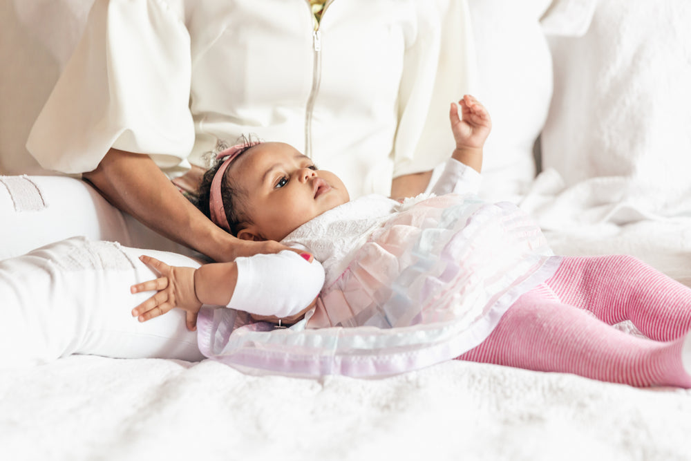 baby girl lying with mom on bed