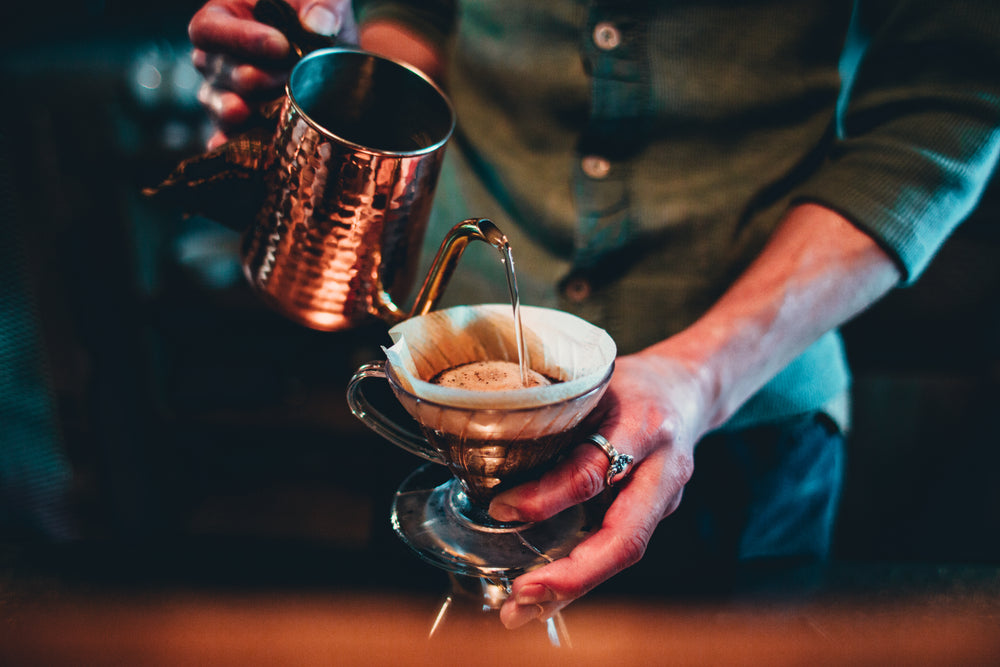 barista pour over coffee from copper kettle