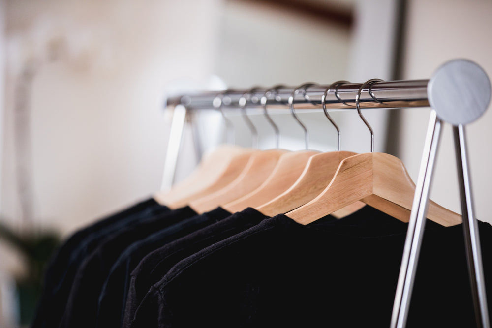 black and blue clothing on a rack in a sunlit shop