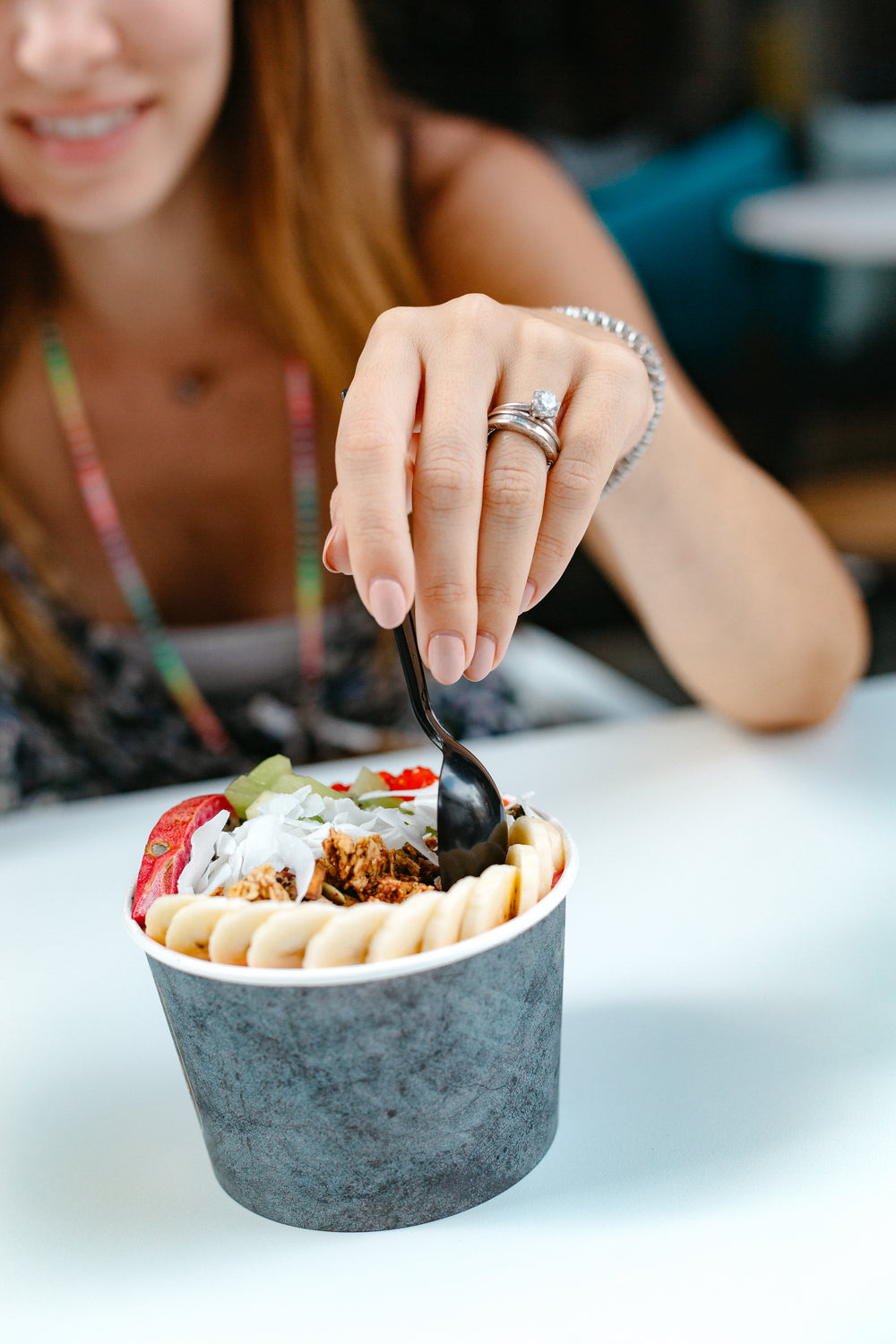 black plastic spoon dips into a bowl of fruit slices