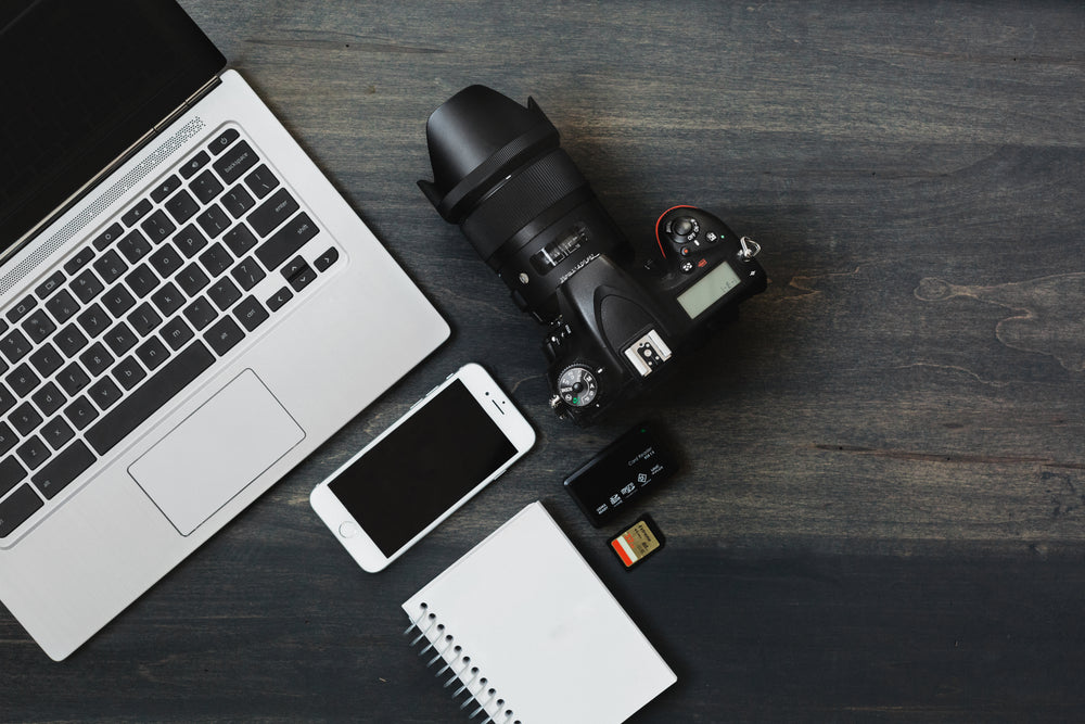 camera, phone, laptop a photographer's desk