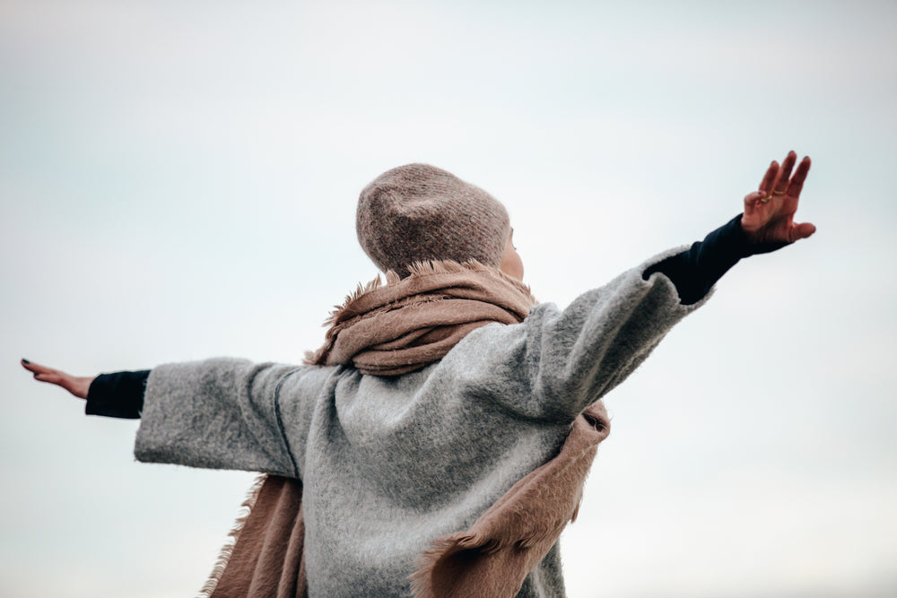 close up of woman spreading arms in autumn breeze