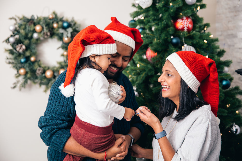 family of three decorates christmas tree