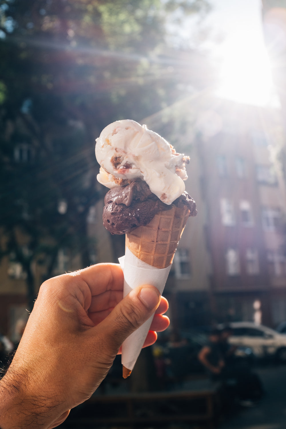 hand holds up a two scoop ice cream cone