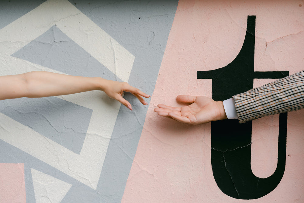 hands reach for each other against a painted wall