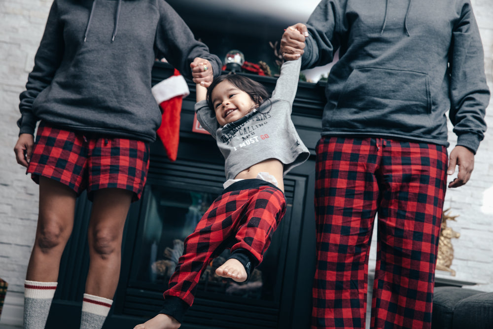 happy boy swinging from parents' arms on christmas morning