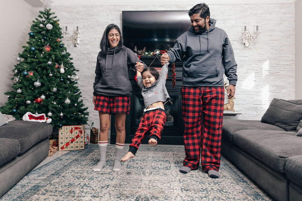 happy couple swings toddler on christmas morning