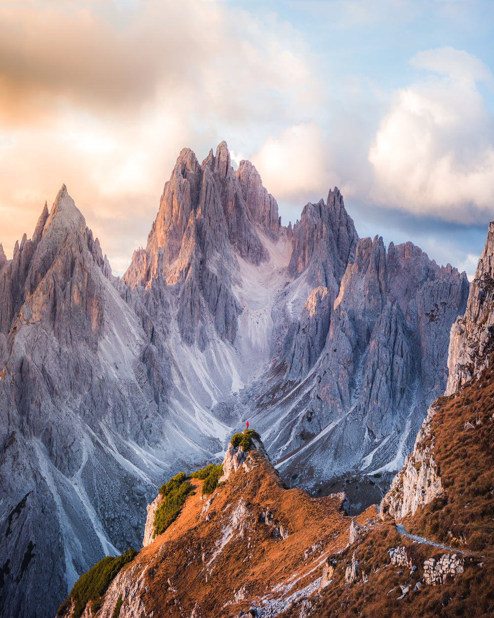 hiker looks up at vertical mountain peaks