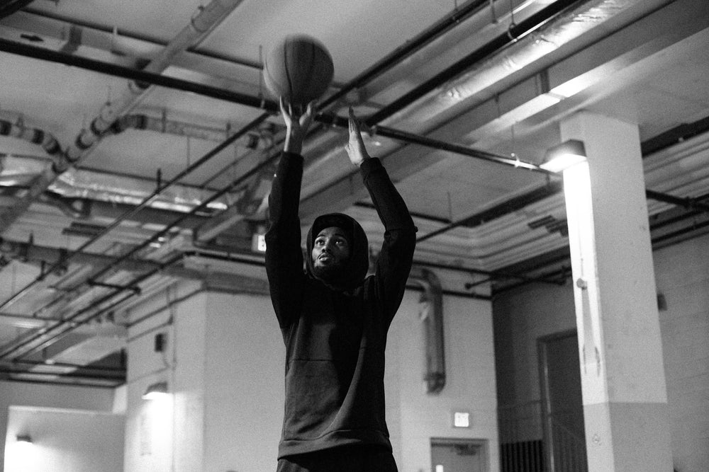 man reaches high and takes a shot with a basketball