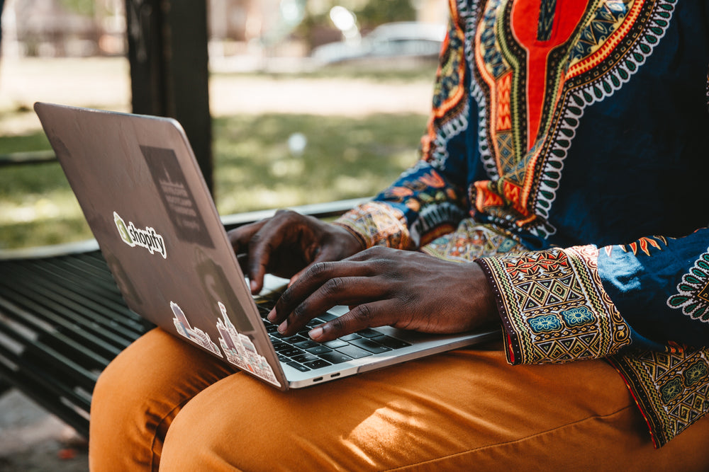 man sits on park bench working on laptop