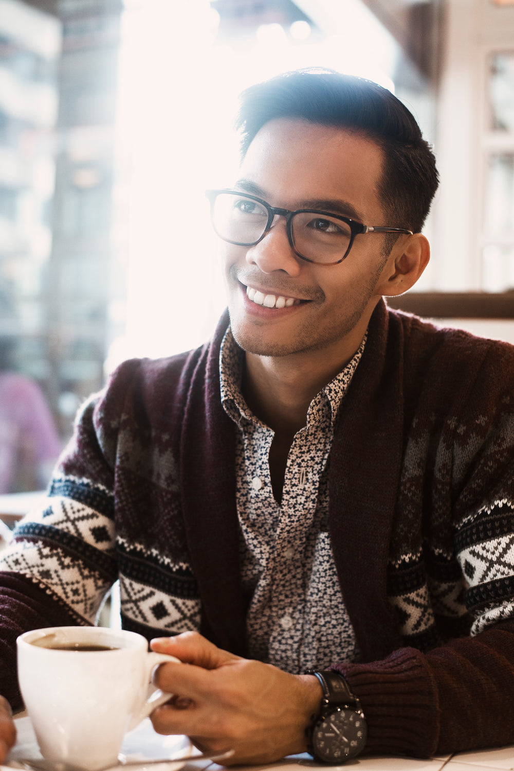 man smiles over coffee in cafe