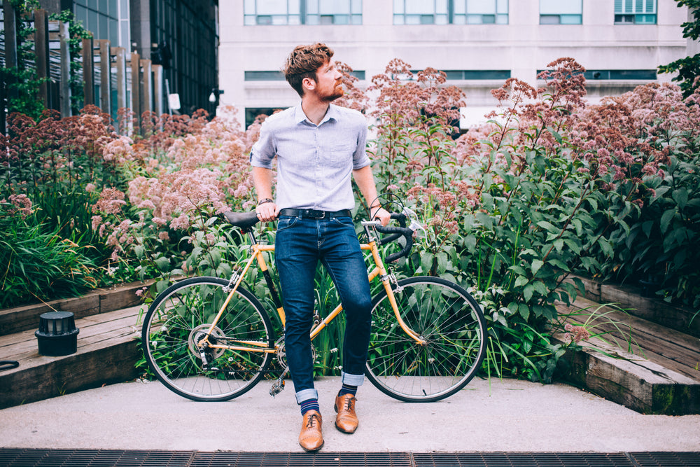 men's fashion man in shirt and jeans leaning on bicycle