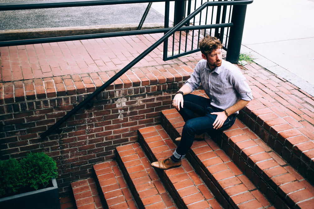 men's fashion man in shirt and jeans sat on steps