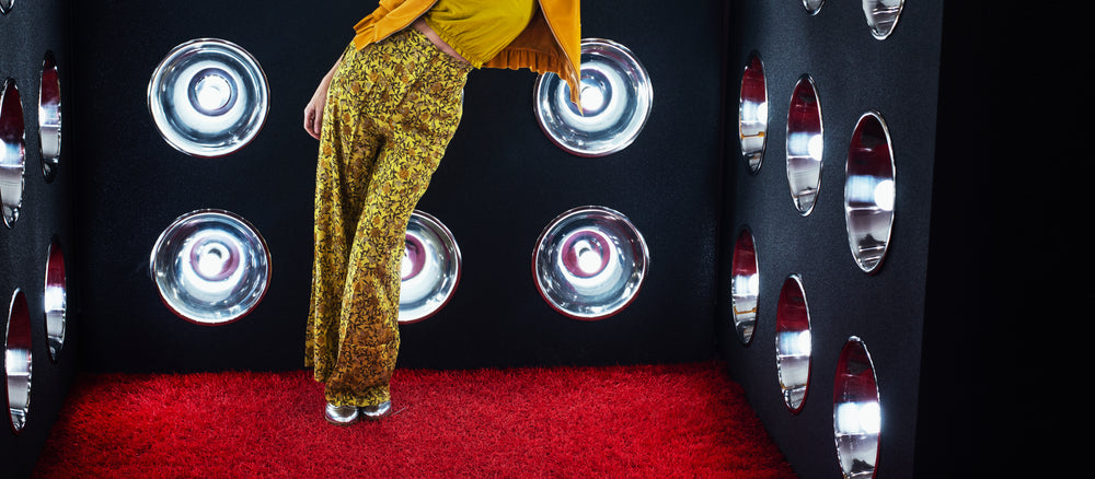 model leaning against a wall of lights atop red shag carpet