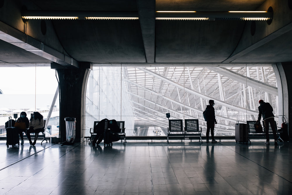 people wait to travel with luggage and face masks