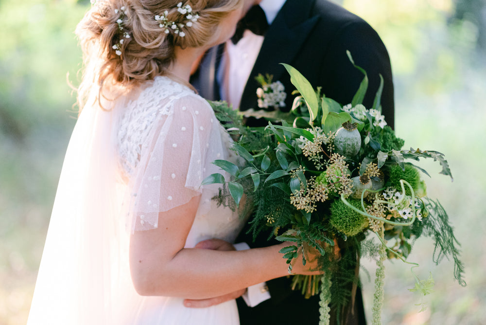 person in a white dress holding a large bouquet of flowers