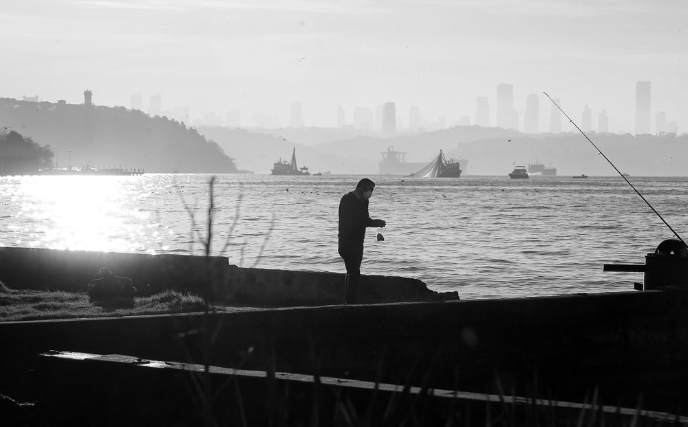 person in mask stands by boats on the water