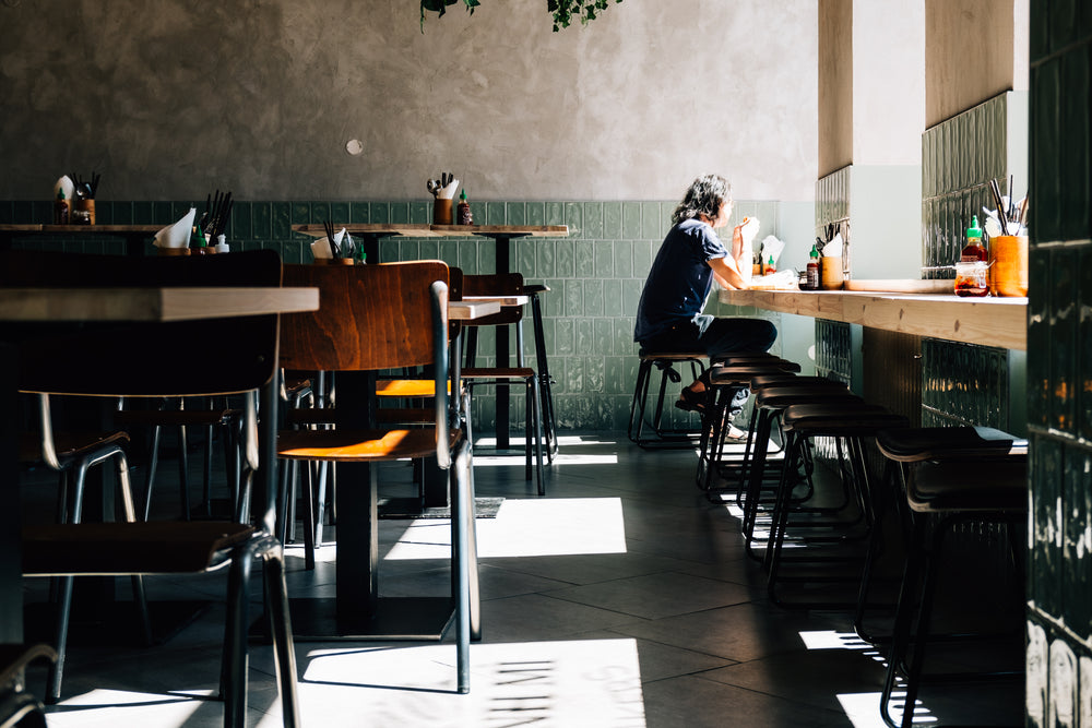 person sits alone by the window of a quiet restaurant