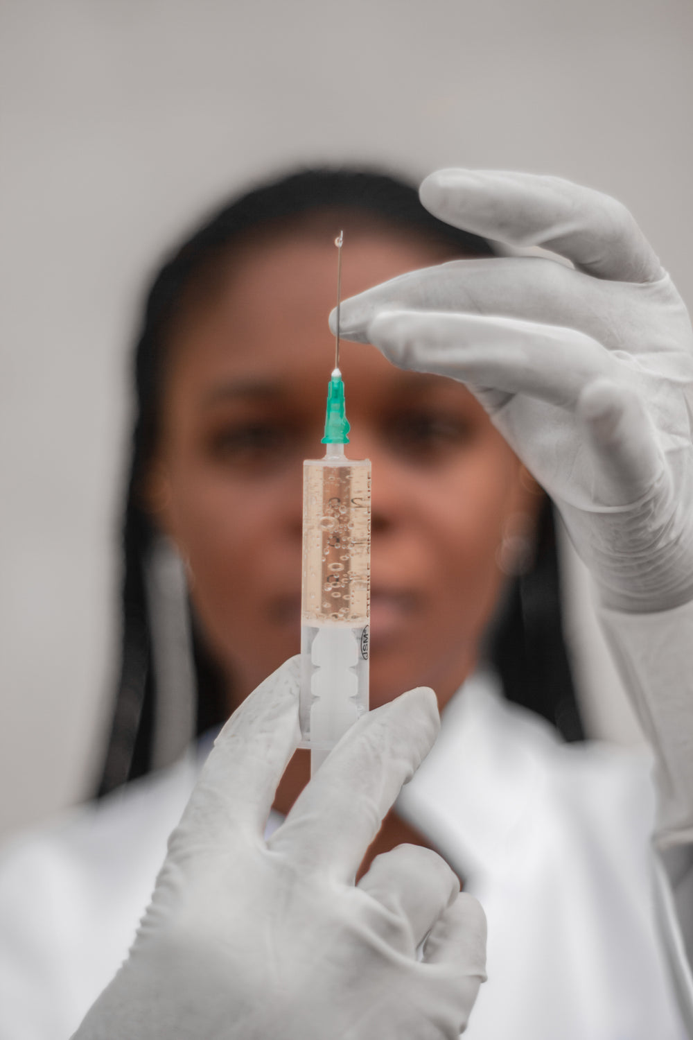 person wearing white gloves prepares a needle