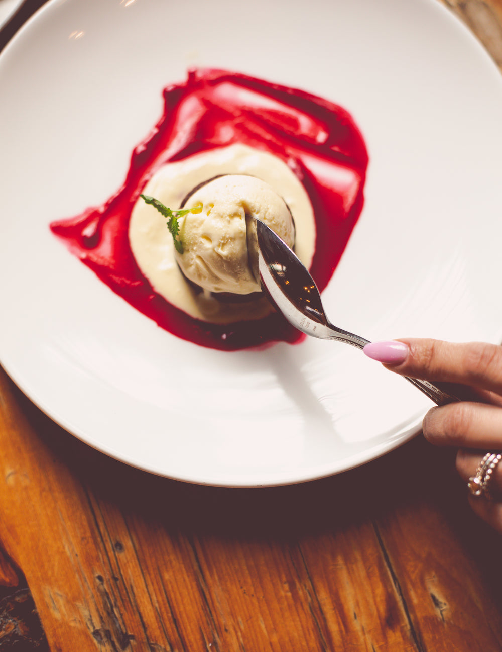 raspberry coulis spread around ice cream