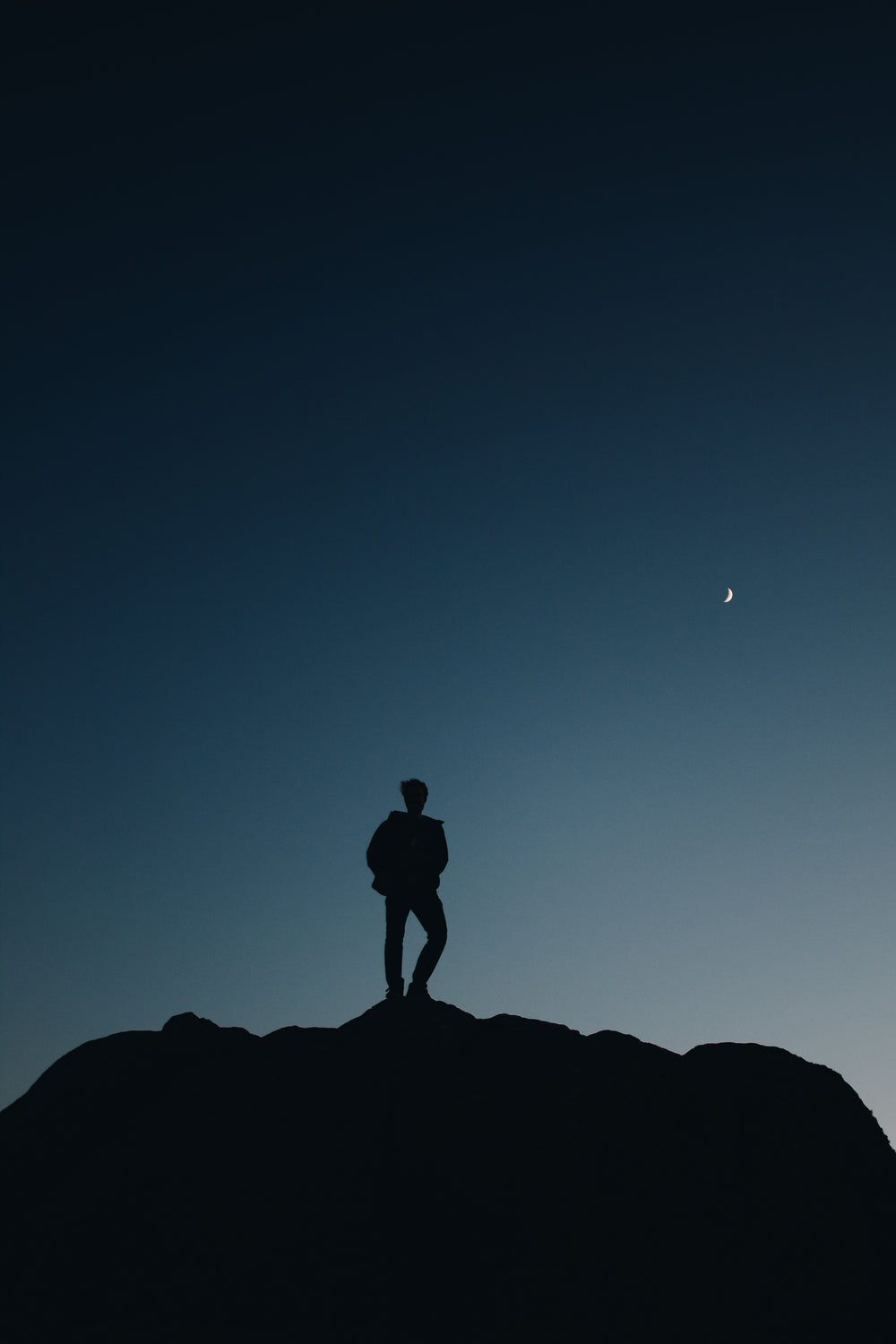 silhouette of a person below crescent moon