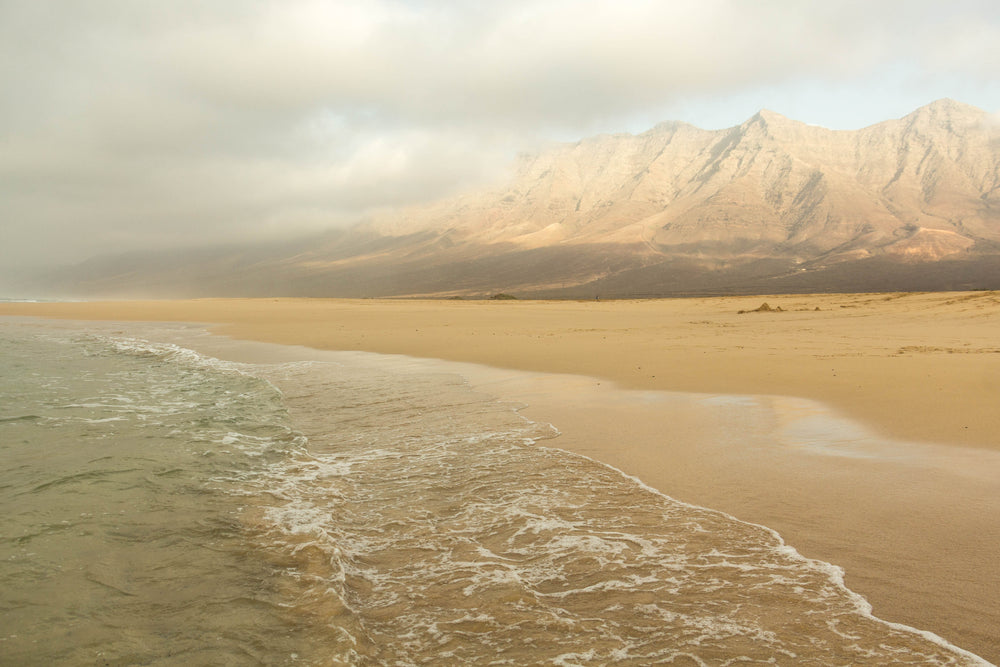 tall mountains look over ocean and sandy beach