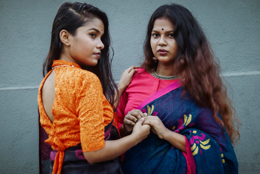 two woman hold hands outside while facing each other