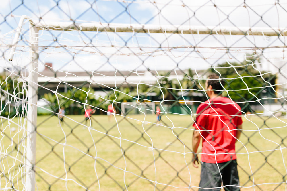 view though lines of a soccer net during game