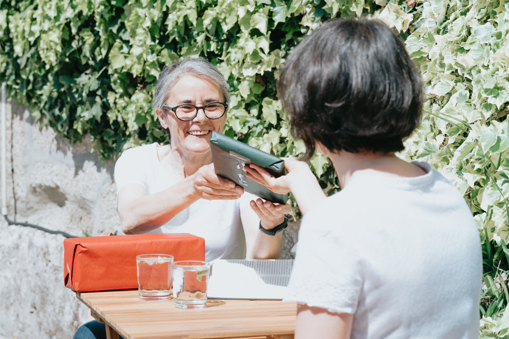 woman accepts a wrapped gift from a friend