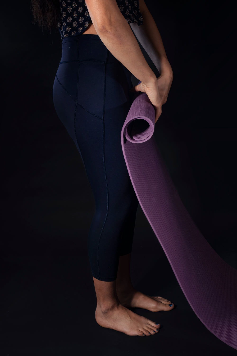 woman rolls up purple yoga mat