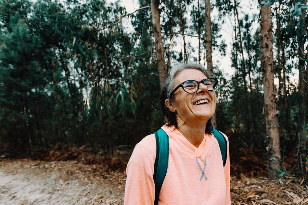 woman tilts her head back and smiles outdoors