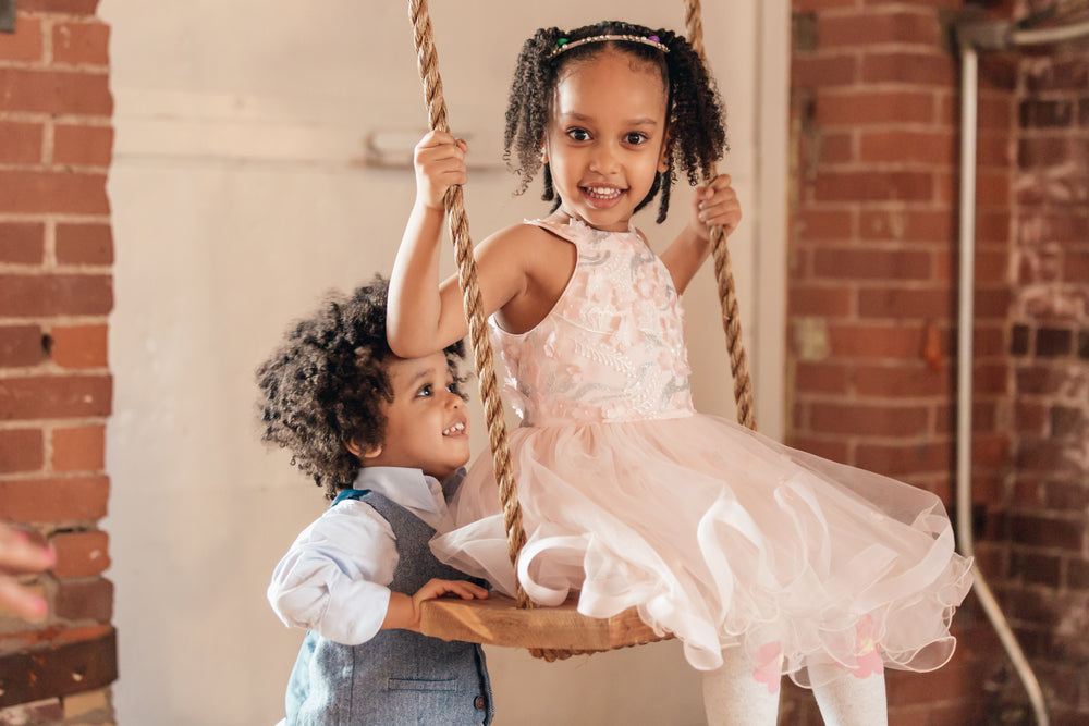 young boy pushes sister on swing