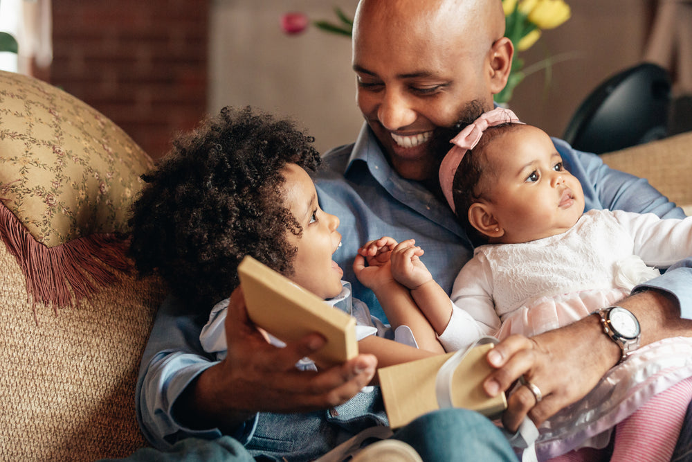 young boy smiles at father holding baby sister